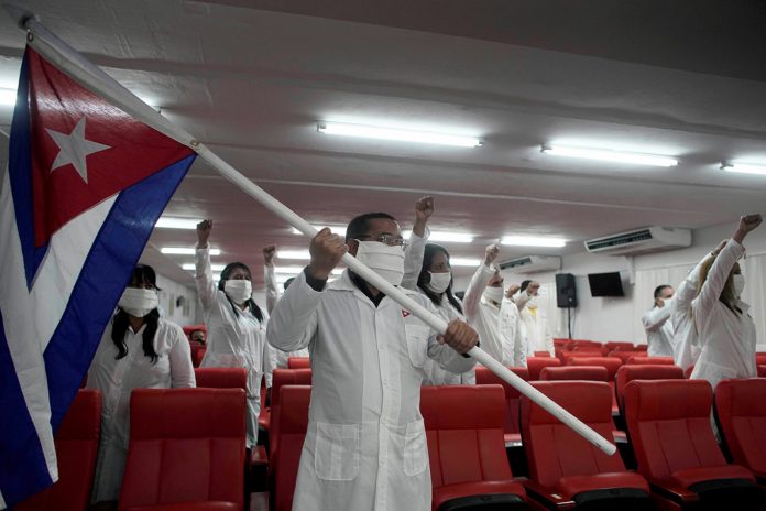 Cuban doctors shout slogans during a farewell ceremony before departing to Guinea to assist, amid the COVID-19 outbreak, in Havana, Cuba on Thursday.Cuban President Miguel Diaz-Canel has declared the coronavirus pandemic 